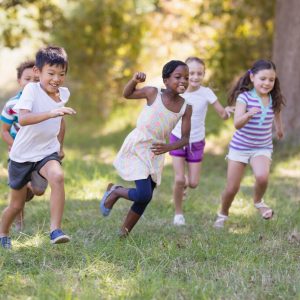 Playful children running on grassy field at campsite