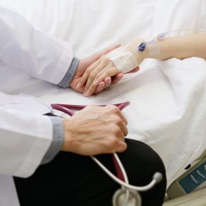 Medical doctor holing patient's hand and comforting her